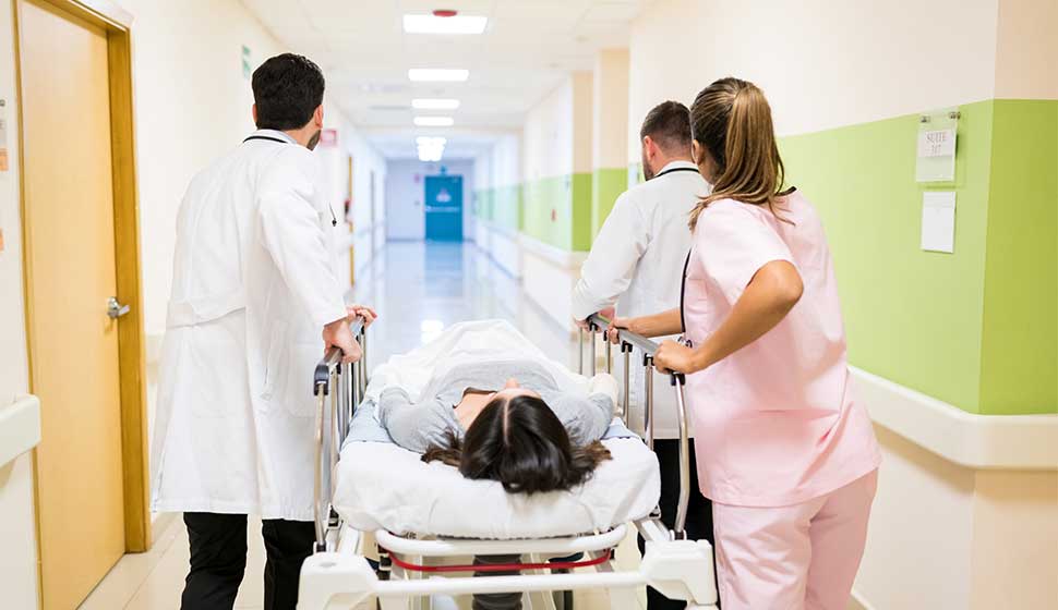 medicos-enfermeras-empujando-paciente-camilla-pasillo-hospital