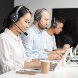 Tres personas trabajando delante de un ordenador portátil con auriculares y micrófono