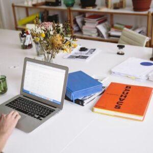 Ordenador portátil y libretas en una mesa blanca