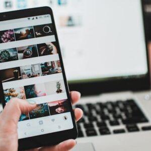Persona Que Sostiene El Samsung Galaxy S8 Negro Medianoche Encendido Donde Se Ven Varias Redes Sociales Cerca De Macbook Pro