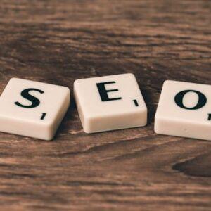 Tres Baldosas De Scrabble En Blanco Y Negro Sobre Una Superficie De Madera Marrón Donde Pone "SEO"